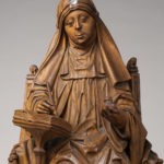 This image features a carved wood sculpture of St. Bridget of Sweden, seated, writing.