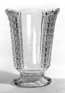 Image of moderately tall, narrow glass vase with four panels—two smooth and two decorated with a starburst pattern—on a small foot.