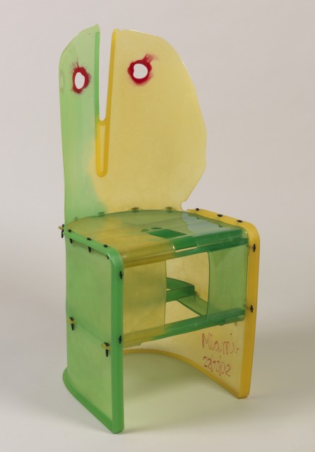 Image features chair, formed of assembled sheets of poured resin in shades of yellows to greens; oval back with attenuated vertical V-shaped split in center, attached to U-shaped seat on base formed of curving sheets. Please scroll down to read the blog post about this object.