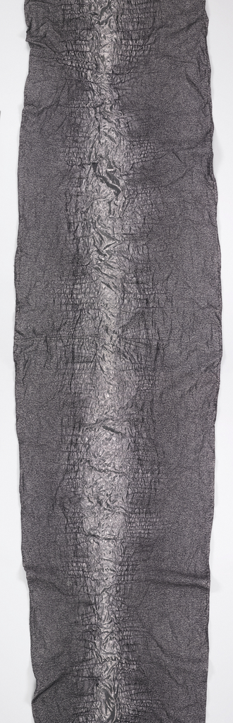 Length of metallic silver and black fabric with a variably puckered surface that resembles the skin of a crocodile.