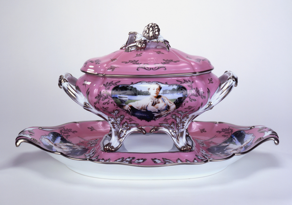 Tureen (a) of bulging and lobed oval form with two scrolling loop handles at either side and four scrolled feet; the white body with pink ground decorated at front and back with large central cartouches showing the artist as Madame de Pompadour in low-cut bodice and wig of silvery curls, with landscape in background; the pink surface embellished with platinum scrollwork and floral sprays, the flower buds rendered as fish; the articulated surfaces of the white handles and feet also picked out with platinum. Interior of bowl white, the floor decorated with scene of fish lying among ropes of pearls, all resting on soft folds of blue fabric. The domed and lobed cover (b), with pink ground decorated with platinum scrollwork and floral sprays as on tureen, and having central knob in the form of large platinum-colored flower buds with white and platinum leaves. The platter (c) of roughly oval shape having a white rectangular well, and wide everted rim, its two scrolled ends forming handles, and decorated with images of the artist as Madame de Pompadour; the articulated surface with pink ground, picked out with platinum scrollwork and floral sprays as on tureen.