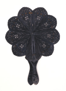 Folding cockade fan, brisé. Sticks and guards of drilled black vulcanized rubber; guards attached to center of two outer sticks, all of which, threaded with ribbon, spread to make a round form.