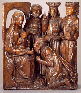 Wood carving of the Virgin, seated at left, with child on her knee. One of the Magi kneels before the child. Behind them, three figures stand on the right.