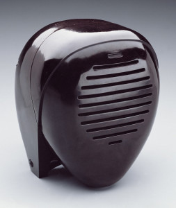 Brown-burgundy ovoid form suggestive of a kerchiefed head or kendo mask; horizontal slits for speaker on the front.