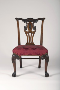 The pierced back splat and crest carved in rococo style with foliate decoration; the knees of the front cabriole legs with carved rococo foliate scroll decoration descending to hairy paw feet. The tapered and raked rear legs with stretcher between. Upholstery replaced.