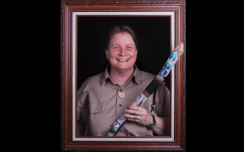 woman standing inside a picture frame holding an ornate walking stick.