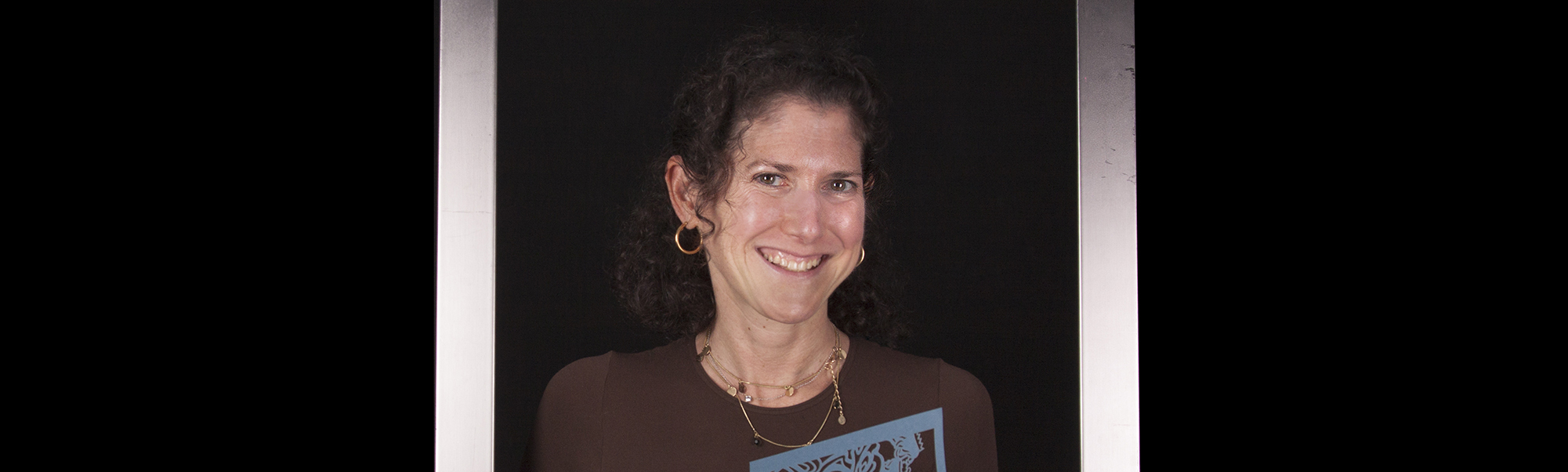 Smiling woman holding a book with colorful die-cut pages.