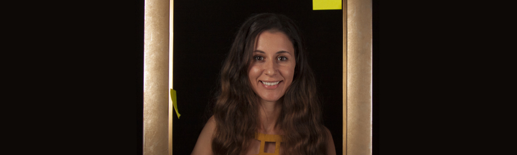 smiling woman standing inside a picture frame holding post-it notes.