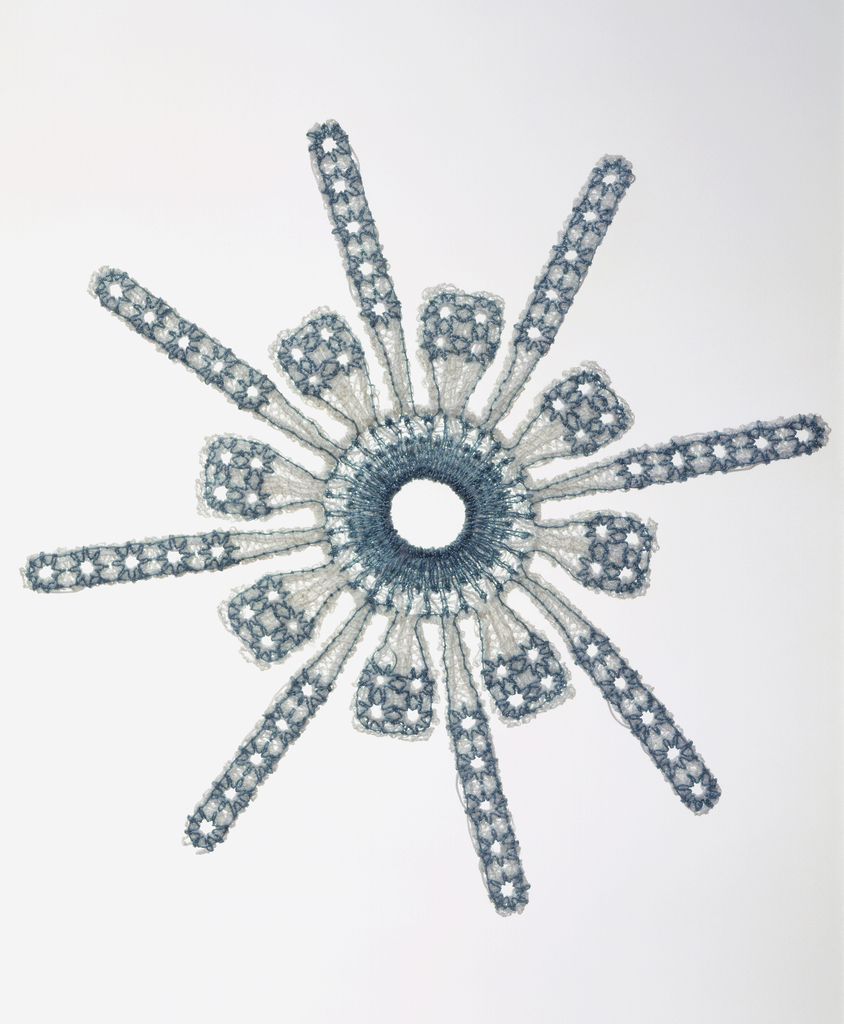 Bioimplantable device for reconstructive shoulder surgery in the form of a snowflake, with eight short and eight long projections from a center ring, machine embroidered in white and blue polyester with the base cloth dissolved for a lace-like effect.