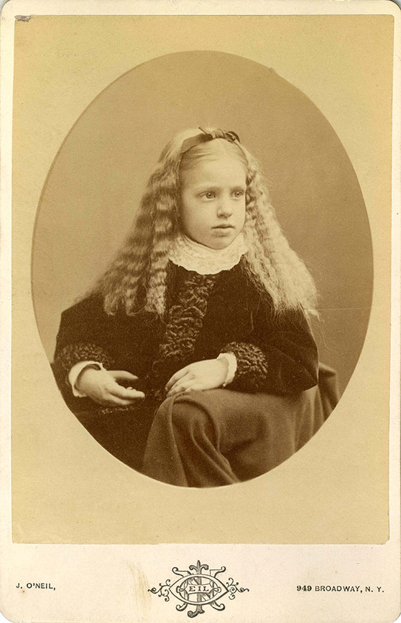 young girl posed for a sepia-toned portrait with long blond hair, crimped from plaits