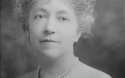 image of a middle aged white woman, black and white old time photo. she wears pearls and has a vague and somewhat tranquil facial expression.