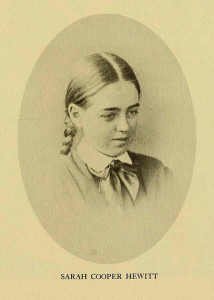 Sepia toned portrait of an adolescent girl, gazing down, with hair in pigtail plaits