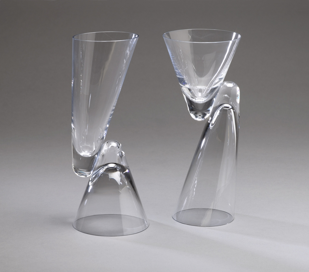 Clear glass form composed of two thin-walled conical bowls, one short and wide, the other long and slightly angled; the bowls facing in opposite directions and joined side-to-side along their thickened vertexes to form a reversible goblet, the mouth of either bowl functioning as the base when upside down. Pair with 1986-36-2.