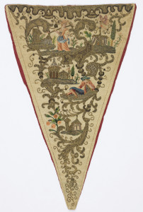 Triangular stomacher in ivory silk, heavily embroidered in gold metallic thread with scrolling leaves framing small buildings, and, in colored silks, a female figure with a rake over one shoulder, a male figure dozing, and a butterfly.