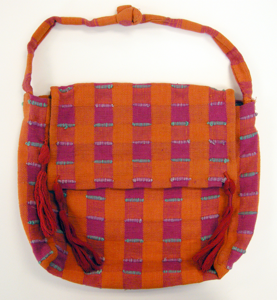 Woven cloth bag with a front flap and strap. Fabric is a hand-woven cotton in which the warps are thinner and more tightly twisted than the loosely-twisted, slubby wefts. Wide stripes in each direction are interrupted occasionally with very narrow ones of 2 warps or wefts each. The vertical stripes are accented with insertions of discontinuous weft which is very thick and raised.