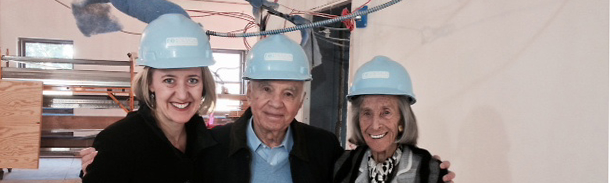 Caroline, Barbara, and Morton pose for a picture in light blue hardhats