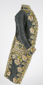 Man's coat of blue and black patterned silk with large-scale floral embroidery in polychrome silks at the center front edges, back vent, pocket flaps and sleeve cuffs, with matching covered buttons. Modern machine-lace at cuffs.
