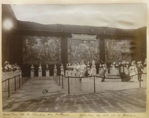Sepia toned photograph of large room with about 30 costumed busts on display. Ropes are cordoning off the exhibition and a sign on the wall hand-painted with name of exhibition in elaborate all-caps lettering.