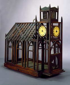 Photo of a birdcage in the shape of a church with clocktower. Made of wood.