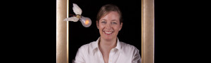 Blonde woman smiling inside a picture frame with flying winged lightbulb over her shoulder