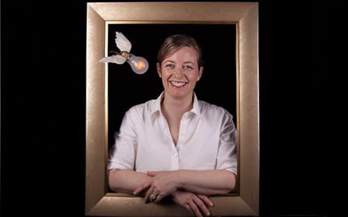 Blonde woman smiling inside a picture frame with flying winged lightbulb over her shoulder