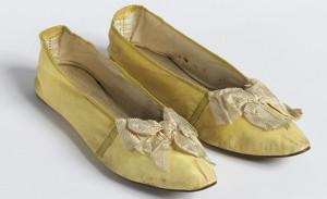 Pair of very old yellow cloth slippers against a pure white backdrop.