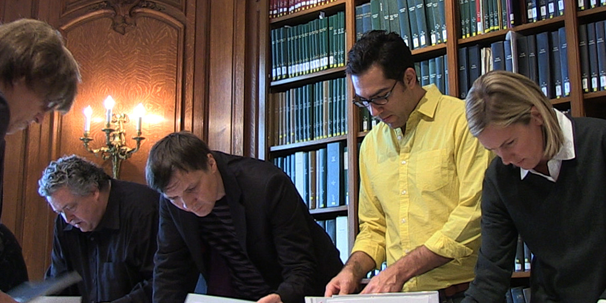 a group of adults gathered around a large table in an elegant library setting.