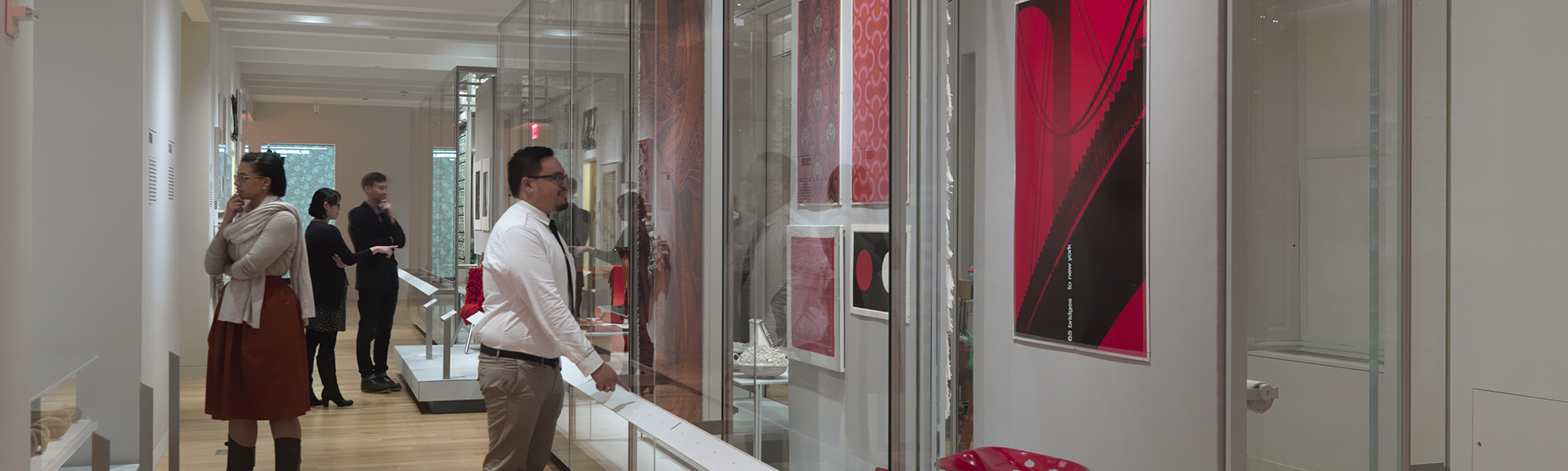 several people in a large museum gallery looking at the items on the walls and in large glass cases.