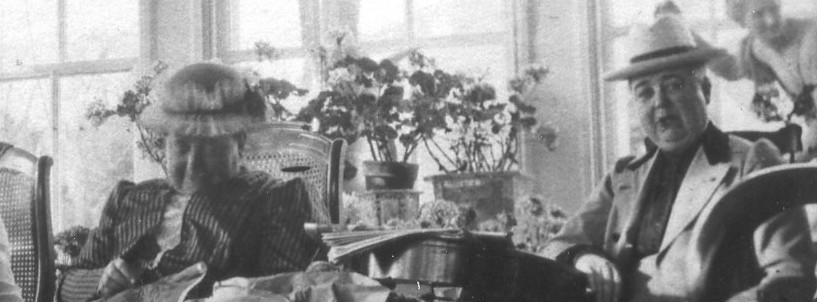 Two hatted women, smiling on a sunny patio