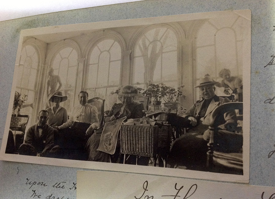 Five people seated on a sunny patio with large windows