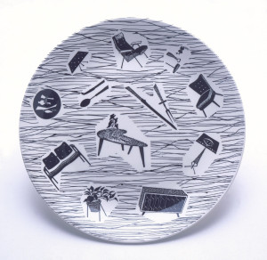Circular molded plate with curved upturned edge; white ground printed with black irregular lines and twelve reserve vignettes with furniture, kitchen tools, plants, etc.