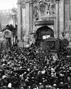 Black and white photo of a crowd of Orthodox Russians standing outside of a church. Some raise wooden icons above their heads.