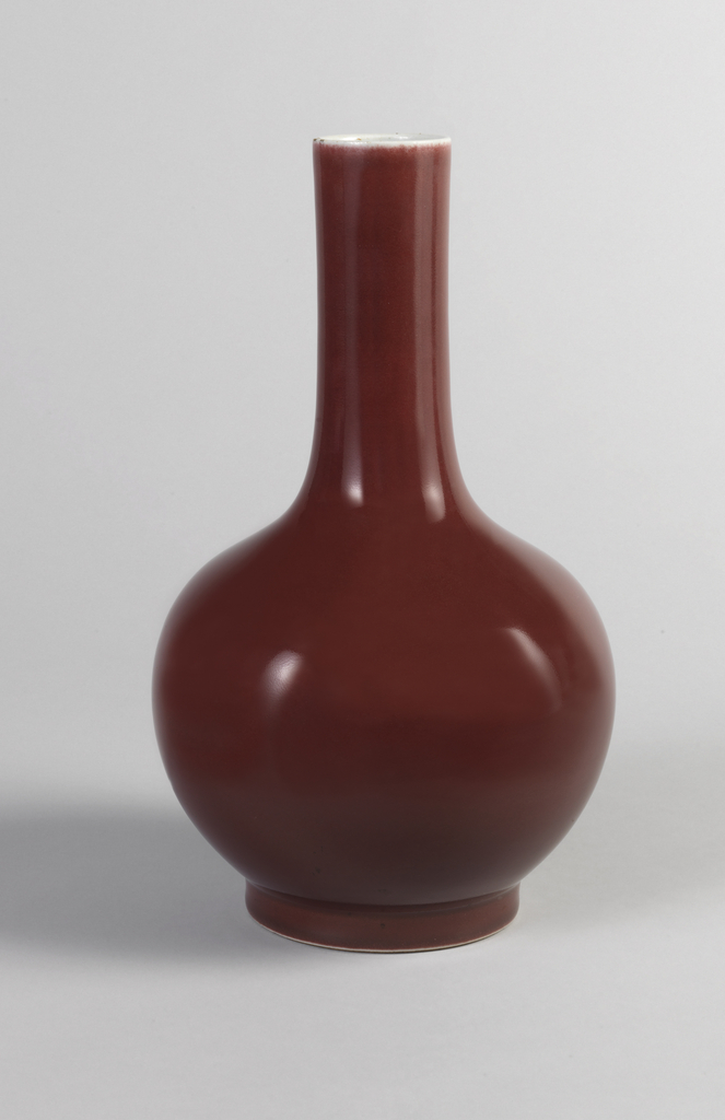 Bottle-form: globular, with straight slender neck, short foot. Coated from white rim to foot with monochrome oxblood color glaze of pear skin texture.
