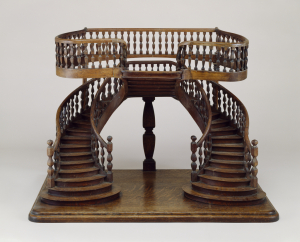 Double-revolution staircase model with curved double staircase with baluster railings, joining on a central landing from which a reverse single staircase rises at right angles, leading to a balcony;