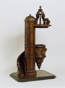 with central column around which a bombe spiral staircase rotates terminating in a similarly curved inverted cone form standing area of the pulpit surmounted by a carved scroll canopy attached above to the column, all resting a rectangular geometrically inlaid marquetry floor-base