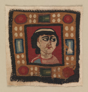 Square of wool tapestry containing an almost frontal bust of a woman with dark hair knotted at the back, gazing to her left, on a red ground. Broad frame imitating gold set with cabochons and rectangular faceted jewels in blue, green, red and white. The woman is wearing a pink garment with perhaps a mantle of sky blue on her right shoulder; she wears a white band in her hair, which is mingled dark blue and brown wefts.
