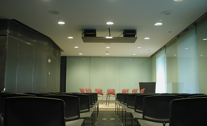 an empty room with chairs on a stage and chairs arranged in rows for the audience.