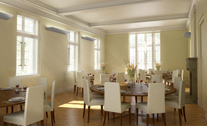 A classy looking white room with round tables, fancy place settings and high-backed white chairs around the tables. Big sunny windows, too.