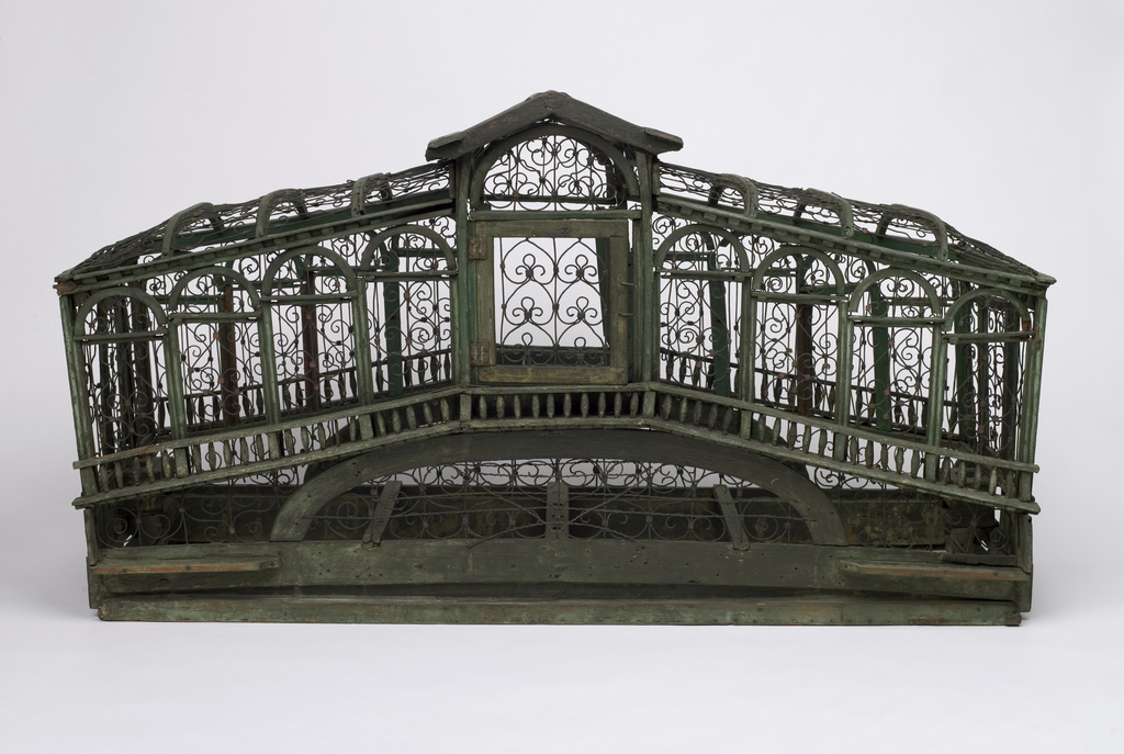 Green painted wooden frame with metal wires, modeled after the Rialto Bridge. Intricate wire scrollwork; four doors; two feed cups; hinged panel at either end for removal of trays (trays missing).