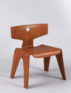 Molded, laminated wood form of T-shaped back, square seat, the sides bending to form four flat legs; front of seat bent down to form short apron; back with small heart-shaped cut-out in center, attached to seat with three metal fasteners. Red-stained finish.