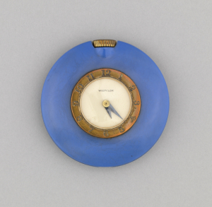 Circular form; smooth blue case surrounding metal band with Arabic numerals encircling white face with black hands; metal stem at top. At center: "WESTCLOX".