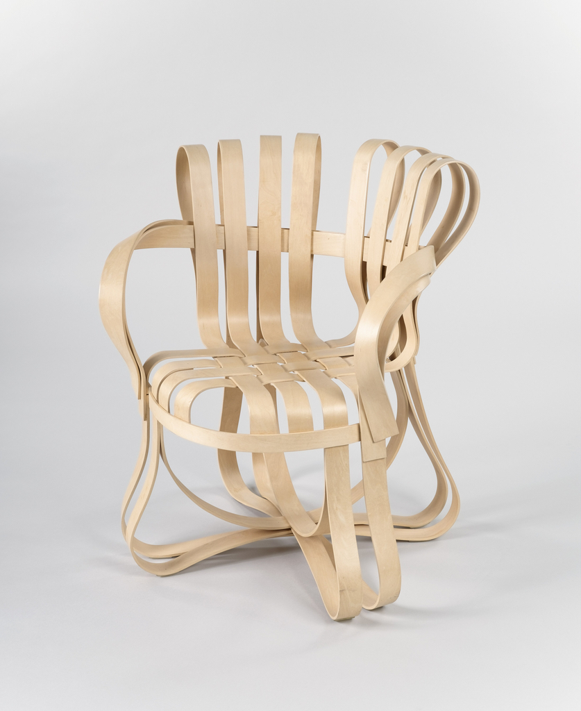 Armchair composed of strips of light-colored maple curved and glued to form back, arms, legs and seat; strips within circular seat woven to form flat surface.