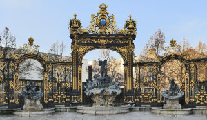 A fountain and behind is a grand metal gate with gilded gold decorations