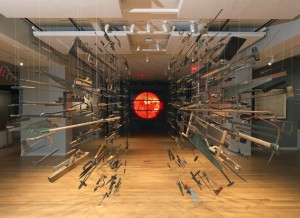 A museum gallery displaying hundreds of tools hanging from the ceiling and a red glowing sun in the background.