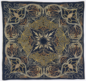 Image features: Silk embroidery in pale colors on dark blue linen. A horizontally and vertically symmetrical floral pattern in the Morris style. Please scroll to read the blog post about this object.
