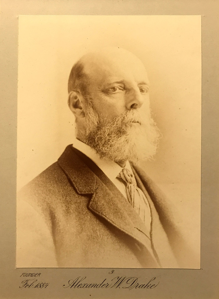 portrait of a bald man with beard and mustache wearing a suit