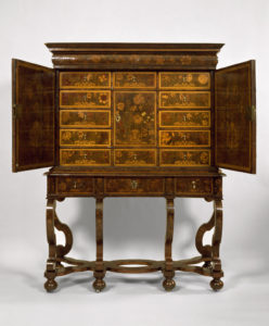 Cabinet on stand with floral marquetry veneer. Cabinet fronted by two large doors with brass lock plates that open to reveal twelve small interior drawers, each with brass pull, and one cupboard door with brass lock plate, all veneered with floral marquetry. Long narrow drawer in cornice molding on top. Stand has long narrow drawer with two brass pulls and one lock plate, supported by six scrolled legs with curved stretchers and bun feet with metal casters.