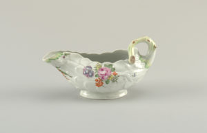 White porcelain leaf-shaped sauce boat with a branch handle. Decorated with small flower details.