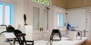 Installation photograph of exhibition Access + Ability, two wheelchairs on a white platform