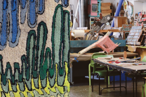A photograph of Creative Growth Art Center studio with a hooked rug hanging on display. Scroll down for information on enrolling in the Creative Growth Workshop at Cooper Hewitt.